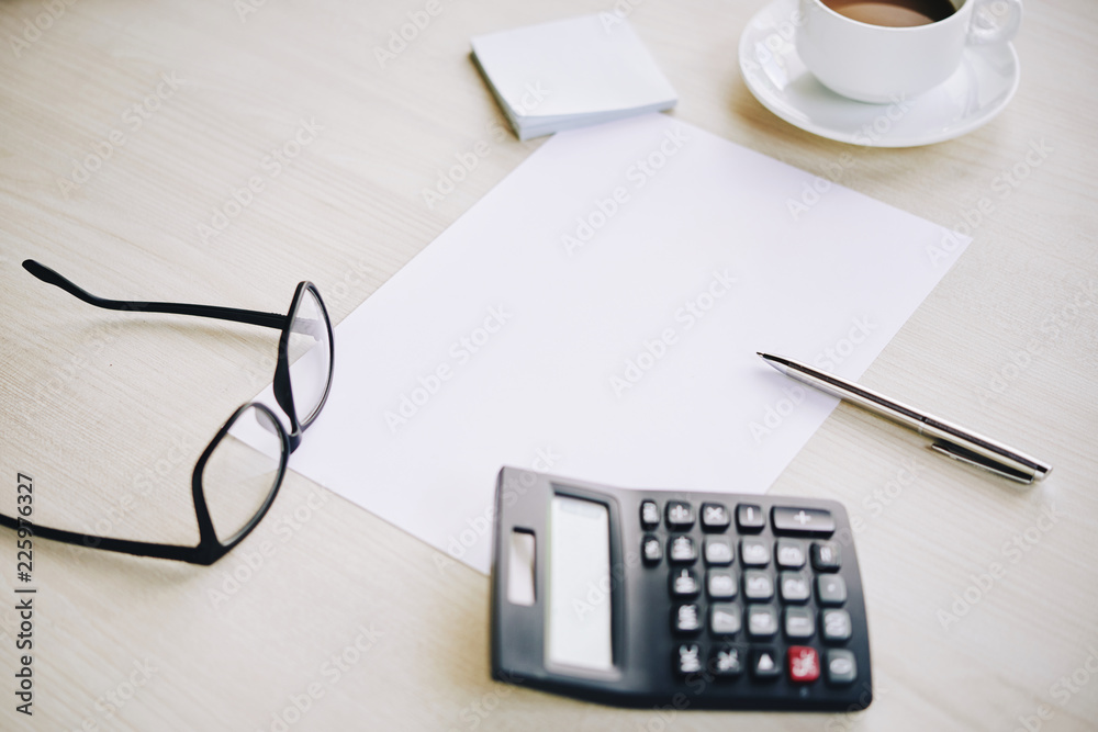 Blank sheet, calculator, glasses and cup of coffee on office table Blank sheet, calculator, glasses and cup of coffee on office table
