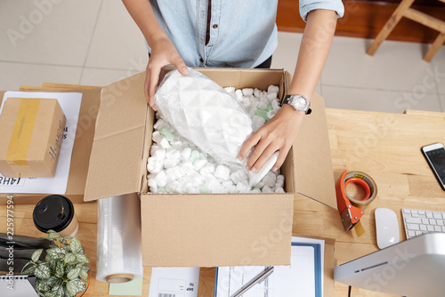 Small business owner packing vase to send it to customer, view from above photo
