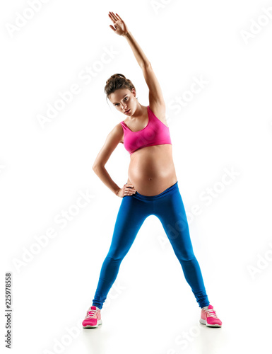 Beautiful pregnant woman warming up, doing fitness exercise on last months of pregnancy isolated on white background. Concept of healthy life