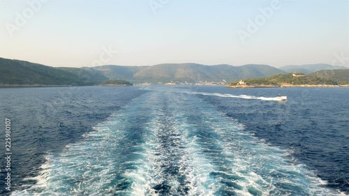 Boat wake on blue sea with island Vis in Croatia and speed boat at background