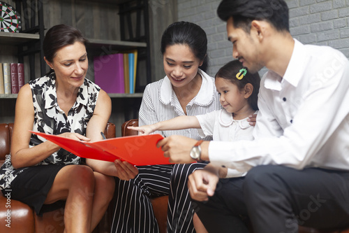 Happy young Asian family talking with psychologist or family counselor In life insurance coverage or real-estate agent house investment or bank worker offers loan or financial advisor with clients.