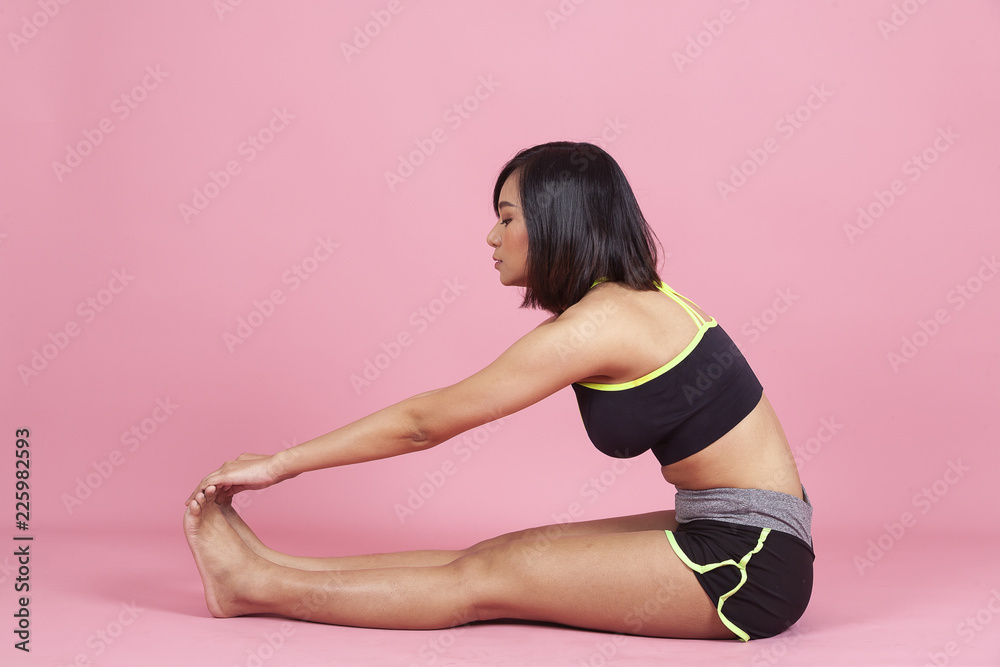 Young Asian woman exercising or stretching in sportswear on pink background. Healthy female warming up or workout in training session. fitness Dynamic movement,Side view. Sport and healthy lifestyle.