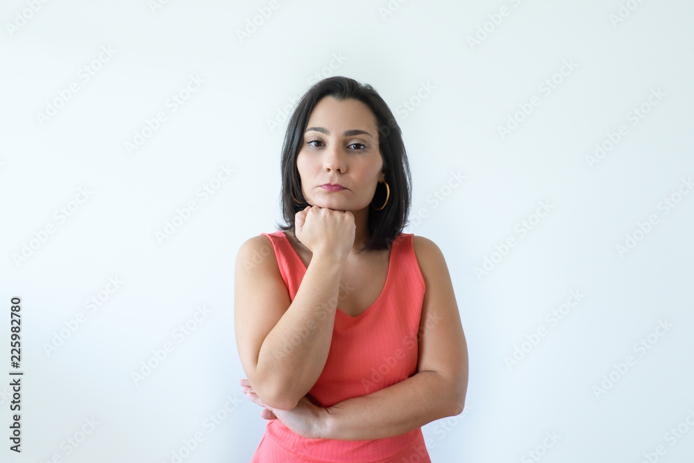 Pensive attractive Caucasian woman with pressed lips holding chin. Pretty middle aged woman in pink dress thinking about new solving problem. Business difficulties concept. Pensive attractive Caucasian woman with pressed lips holding chin. Pretty middle aged woman in pink dress thinking about new solving problem. Business difficulties concept.