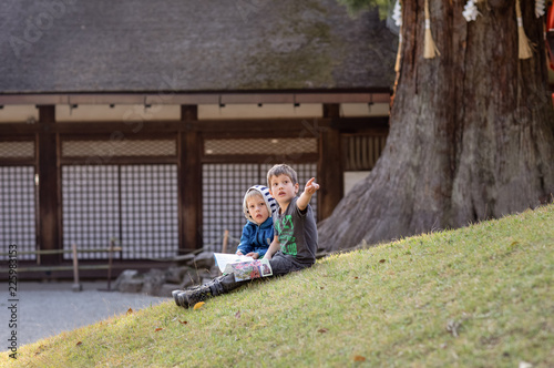 Children reading the tourist guide to a zen temple and pointing at somthing