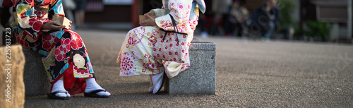 Two girls dressed in kimonos sitting and sharing snacks out of boxes