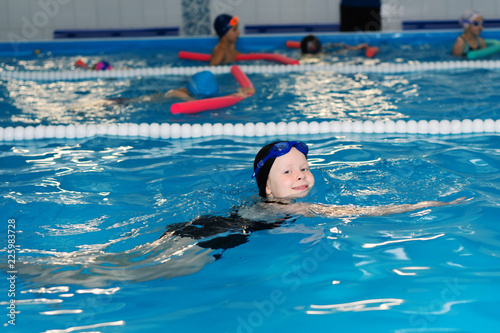 Fototapeta Naklejka Na Ścianę i Meble -  swimming lessons for children in the pool - beautiful fair-skinned girl swims in the water
