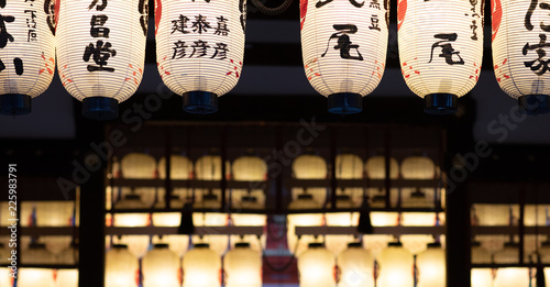 Lit lanterns hanging from a roof of a japanese temple at night