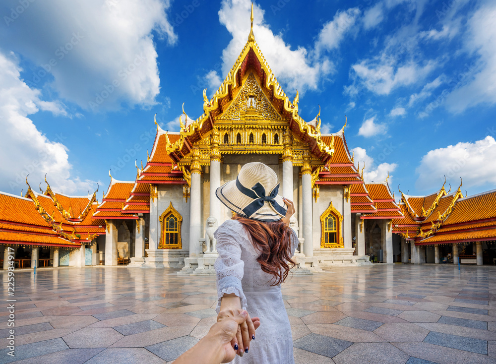 Obraz premium Turystki trzymające mężczyznę za rękę i prowadzące go do Wat Benchamabophit lub marmurowej świątyni w Bangkoku w Tajlandii.