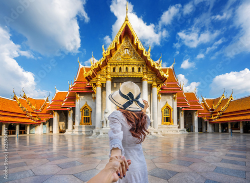 Women tourists holding man's hand and leading him to Wat Benchamabophit or the Marble Temple in Bangkok, Thailand. photo