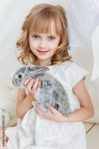 Cute girl hugging with rabbit while sitting on the floor at home