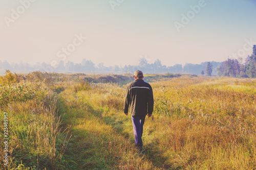 Foto A man walking along a country road through the field early in the morning