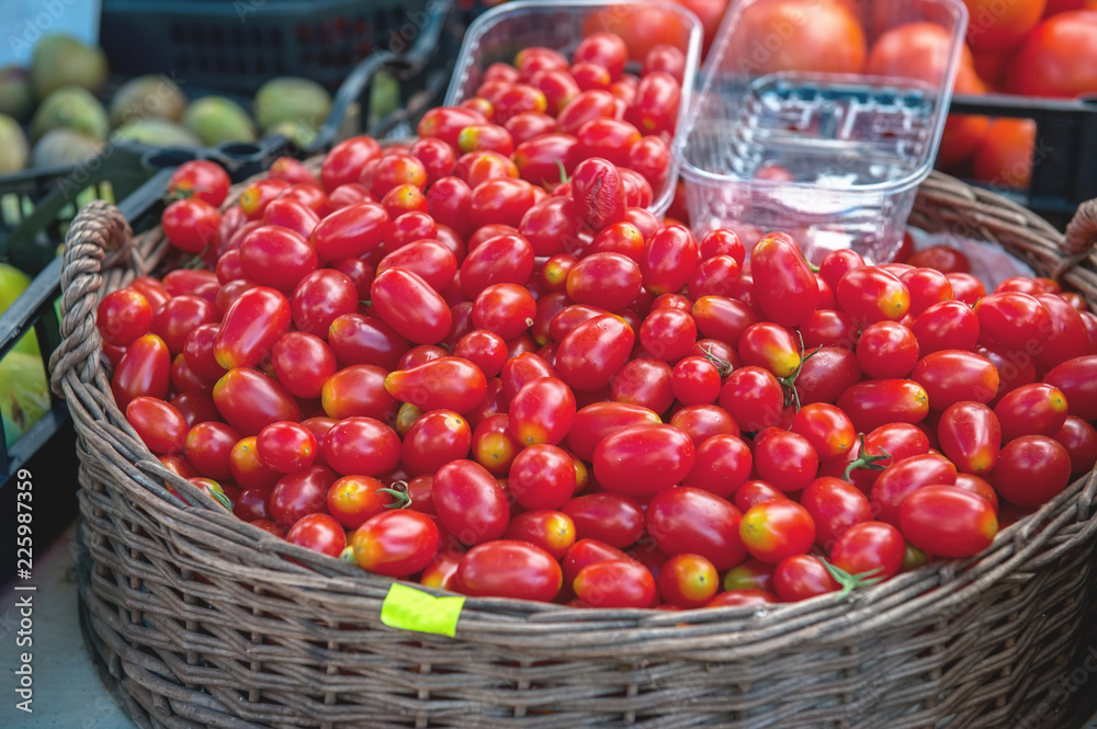 Red ripe cherry tomatoes sell at the farmer's market on a Sunny autumn day in a wicker basket Red ripe cherry tomatoes sell at the farmer's market on a Sunny autumn day in a wicker basket