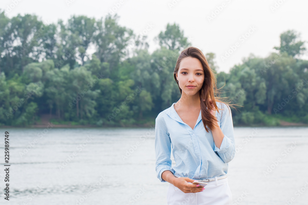 Horizontal portrait of a beautiful attractive woman on the waterfront background. Young girl looking at camera and smiling.