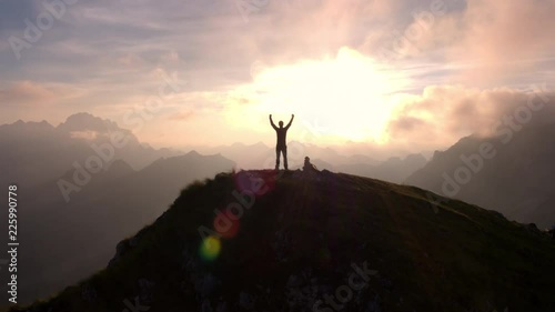 Aerial - Moving above silhouette of a man standing on top of the mountain photo