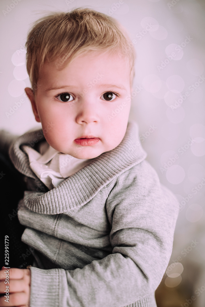 Cheerful little baby boy playing near Christmas tree, gold and beige pastel c Cheerful little baby boy playing near Christmas tree, gold and beige pastel c