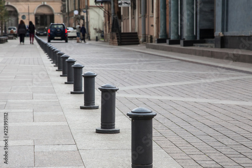 A row of iron bars, people and cars on a pedestrian street