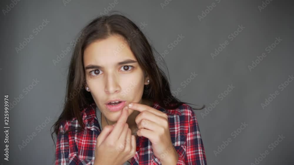 Acne, pimple, clear and clean, oily, dry skin concept. A young lady looks in the mirror and sees problems with her face