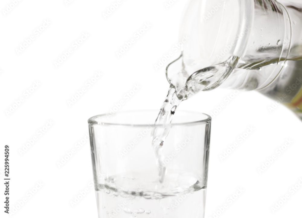 Hand pours water into a glass glass Cup from a glass jug. Close up. Isolated on white background Hand pours water into a glass glass Cup from a glass jug. Close up. Isolated on white background