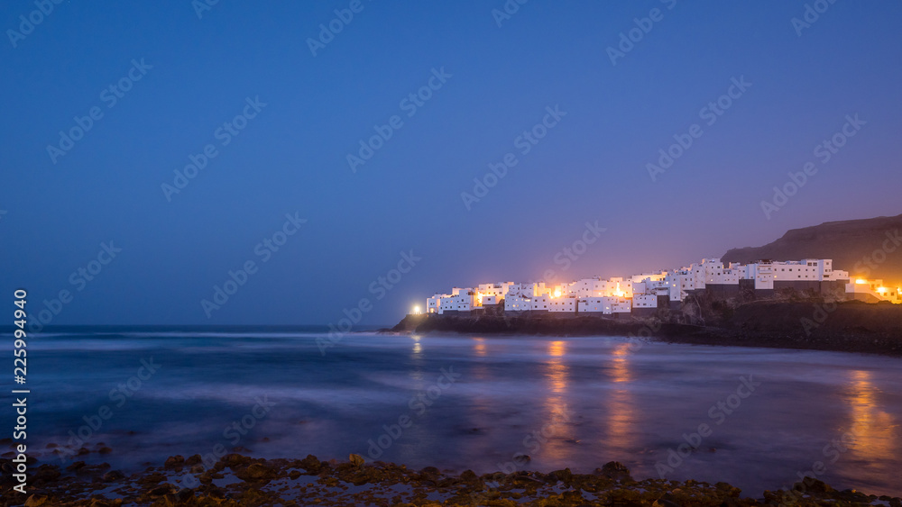 beautiful white village on a rock by the sea at blue hour