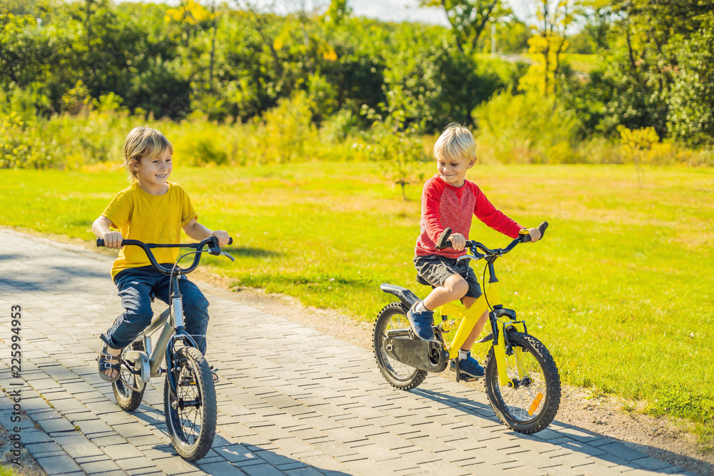 Two happy boys cycling in the park Two happy boys cycling in the park