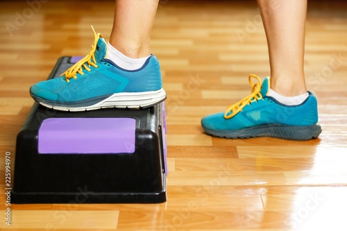 The girl in sneakers is engaged on the step-platform for fitness. Feet on the step for sports. Close up