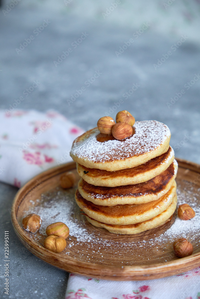 pancakes sprinkled with nuts hazelnuts on a plate with a napkin on a concrete background pancakes sprinkled with nuts hazelnuts on a plate with a napkin on a concrete background