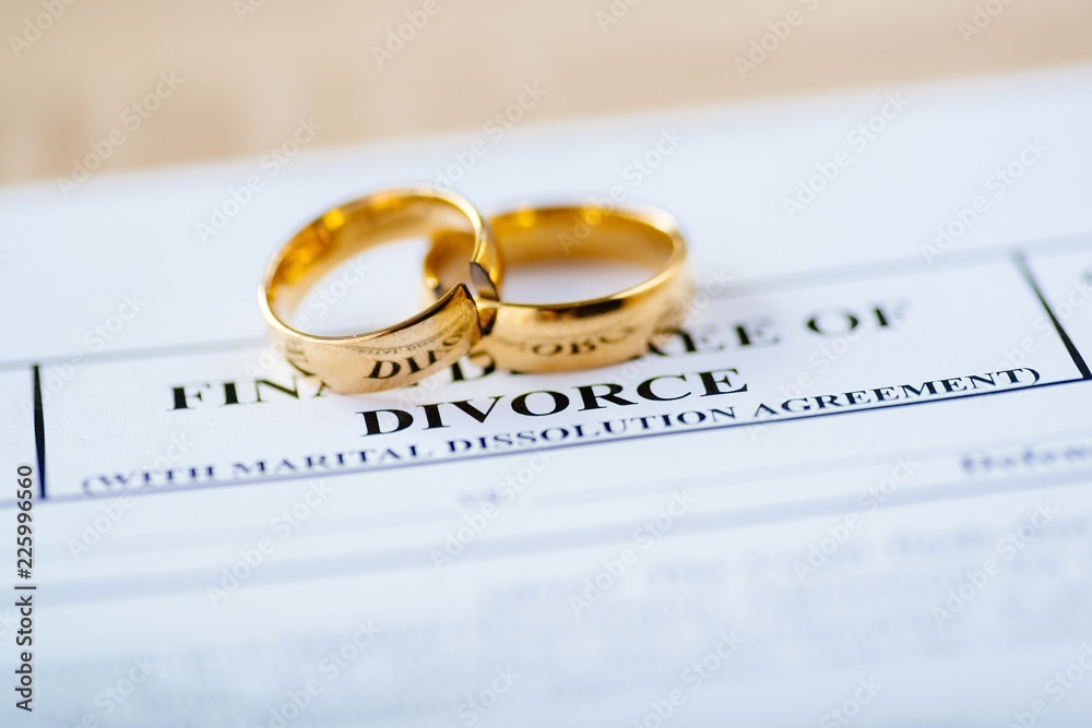 Two broken golden wedding rings divorce decree document