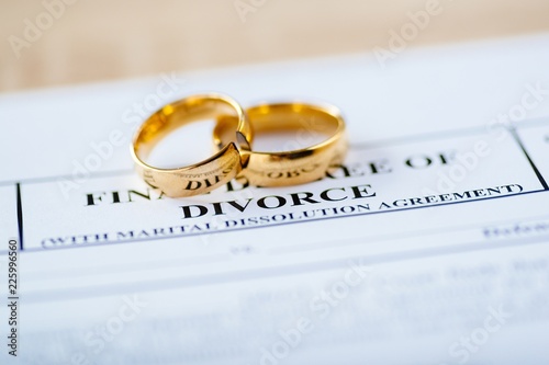 Two broken golden wedding rings divorce decree document