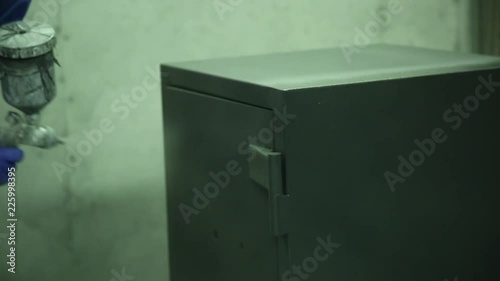 Painting of the safe. Powder painting of the safe. The pulvirezator for powder painting is used. Close up. Hall for painting. Specialist carries out the pendular movements by a hand when painting. 