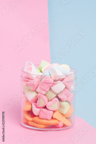 Creative arrangement of colorful candies and sweets on pastel blue and pink background