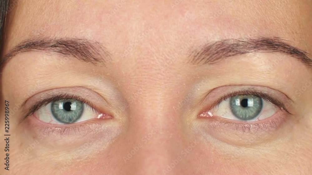 Close up female eyes blinking and looking into camera. Adult woman winking eye