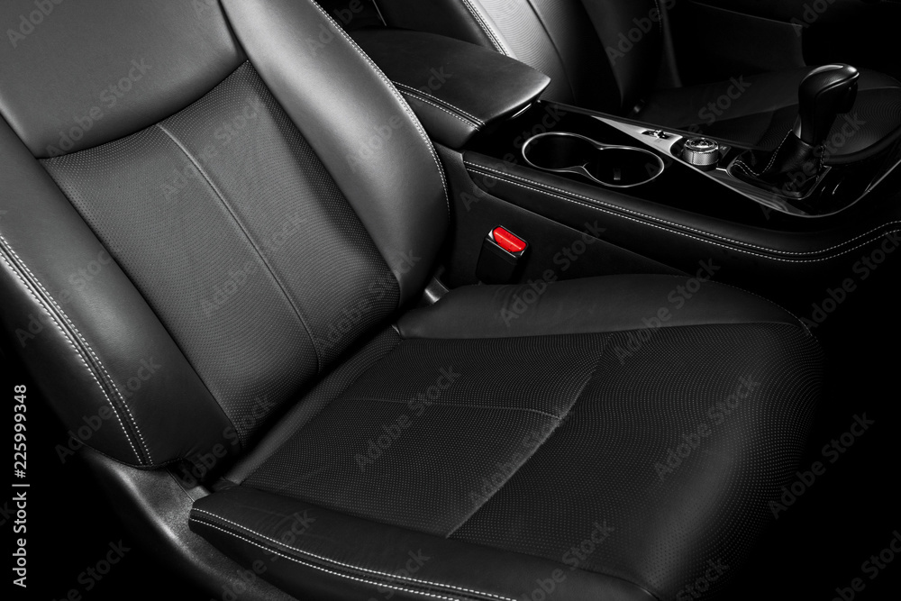Obraz premium Modern Luxury car inside. Interior of prestige car. Comfortable leather seats. Black perforated leather cockpit with stitching. Steering wheel and dashboard. Automatic gear stick shift. Car detailing