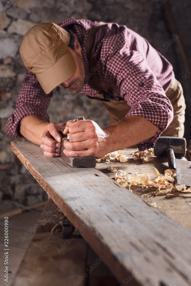 Carpenter smoothing out long wooden beam with tool Carpenter smoothing out long wooden beam with tool