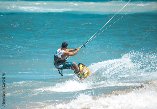 Kitesurfing. The young man is flying on the sea wave on the Board.