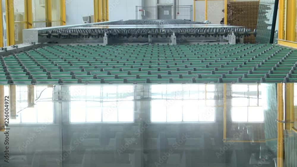 A sheet of glass moves on the roller table. Automatic removal of flat glass from the conveyor line.  Glass conveyor line