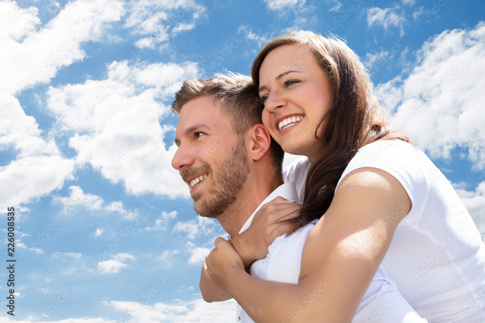 Happy Man Giving Piggyback To His Wife At Beach Happy Man Giving Piggyback To His Wife At Beach