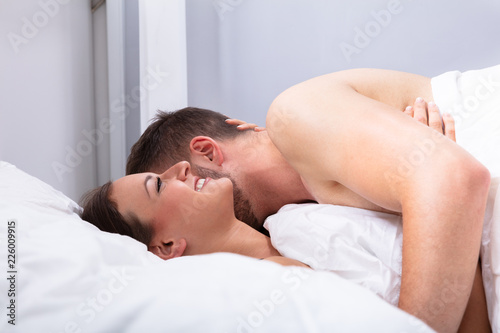Man Kissing Woman On Bed