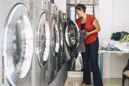 nice young brunette wash and clean some dresses and clothes at the laundry mat service automatic machine. Business activity for people with no much time and stress. city shop