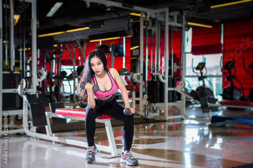Fototapeta Naklejka Na Ścianę i Meble -  Fitness Asian women performing doing exercises training with dumbbell sport in sport gym interior and fitness health club with sports exercise equipment Gym background.