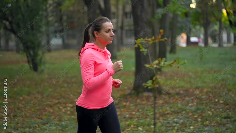 Close up of woman running through an autumn park at sunset. Slow motion Close up of woman running through an autumn park at sunset. Slow motion