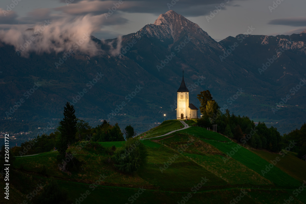 Church on the hill at night.Beautiful scenery at Jamnik, Slovenia. Panoramic view of the Alps behind the church.