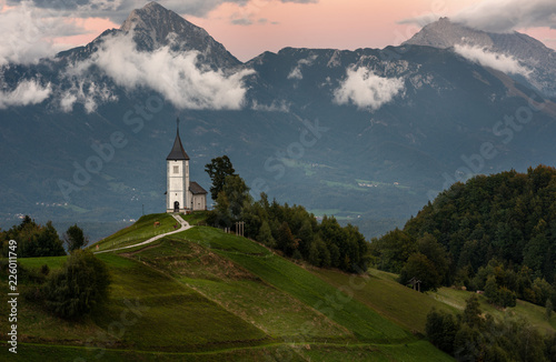 Church on the hill at sunrise. Beautiful scenery at Jamnik, Slovenia. Panoramic view of the Alps behind the church.