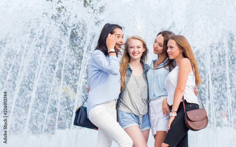 Pretty student girls having fun outdoors. A group of attractive cheerful women talking near the fountain in the city. Pretty student girls having fun outdoors. A group of attractive cheerful women talking near the fountain in the city.