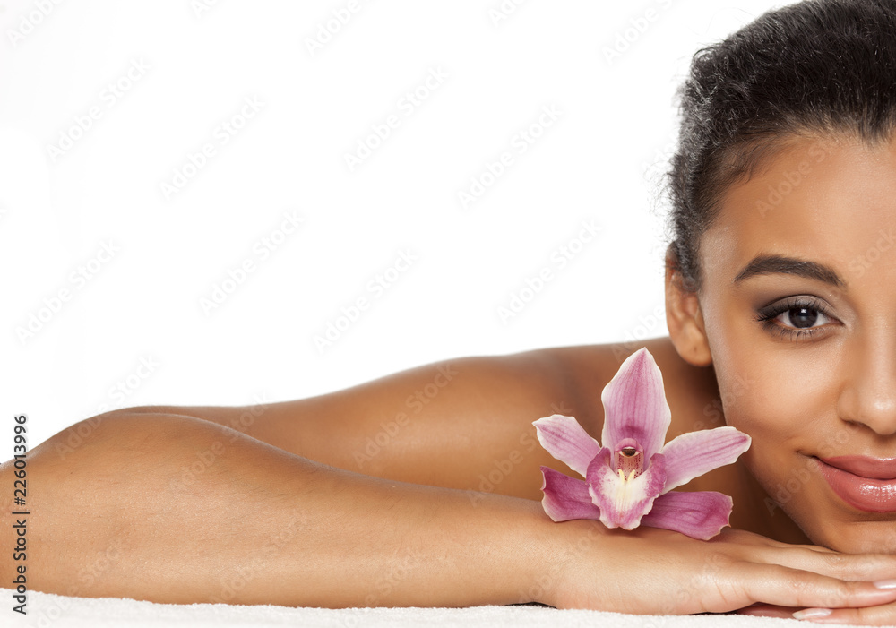 half portrait of young beautiful dark-skinned woman with orchid lying on a white background half portrait of young beautiful dark-skinned woman with orchid lying on a white background