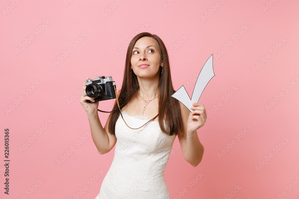Pensive bride woman in wedding dress looking up hold retro vintage photo camera and check mark choosing staff photographer isolated on pink background. Wedding to do list. Organization of celebration. Pensive bride woman in wedding dress looking up hold retro vintage photo camera and check mark choosing staff photographer isolated on pink background. Wedding to do list. Organization of celebration.