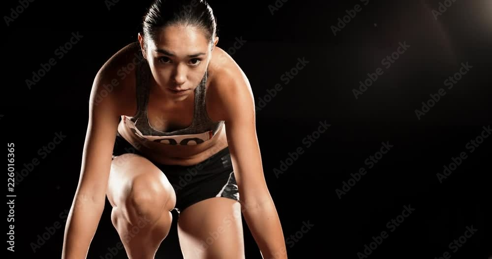 Athlete ready to start. Young female runner preparing for blasting off on sports track of stadium, training before competition 4k