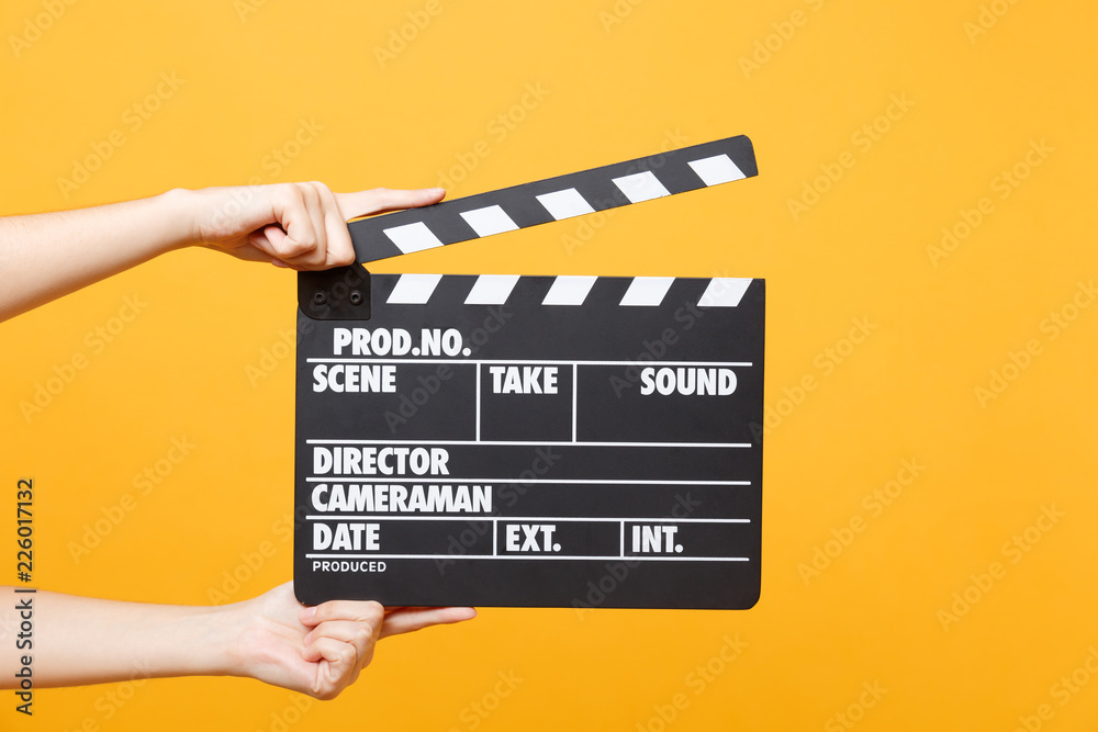 Close up female holding in hand classic director clear empty black film making clapperboard isolated on trending yellow orange background. Cinematography production concept. Copy space for advertising