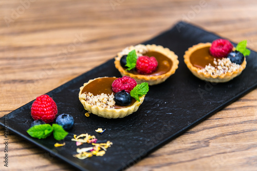 Homemade shortbread tartlets with custard cream and fruit..Tartlets dessert, pastry cakes with fresh fruit on wooden background