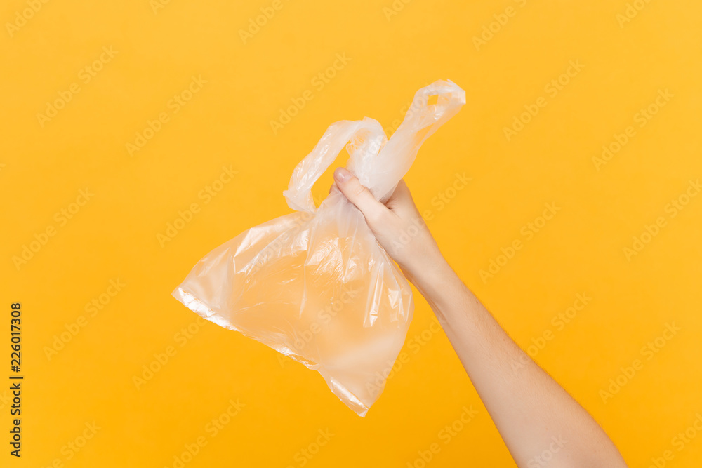 Close up female hold in hand clear empty blank transparent plastic bag full  with air for takeaway isolated on bright yellow background. Packaging  delivery service concept. Copy space. Advertising area Stock Photo