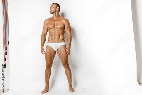 Strong stripped muscle male model in white underwear on white isolated font background